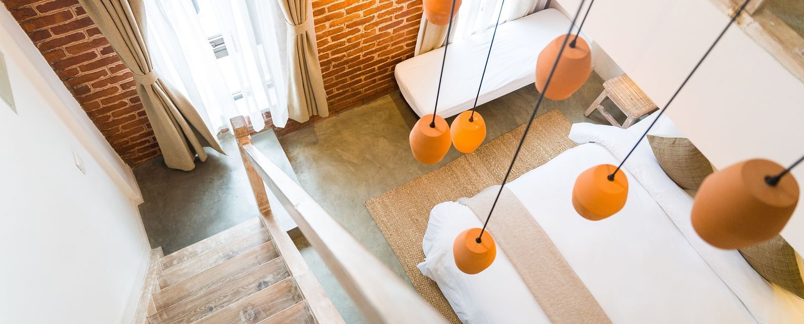 An aerial shot of the deluxe loft room with a staircase and chandelier hanging above it - The Nanee