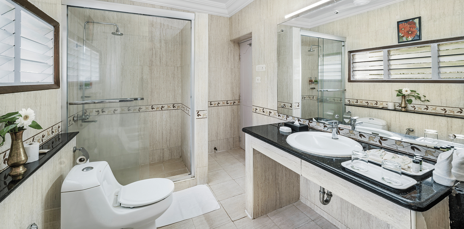 An image of a washroom which is brightly lit with toiletries and a big mirror - GReaT Trails River View Resort Thanjavur By GRT Hotels