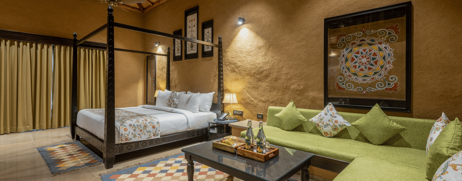 A stylish bedroom at Aamaghati Wildlife Resort with a four poster bed, colourful rugs, and a cosy seating area for a perfect stay.