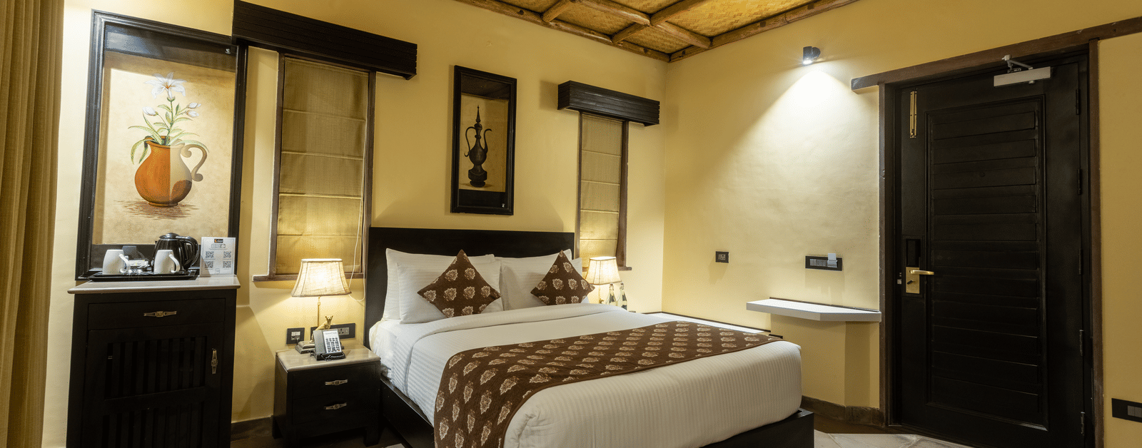 A contemporary bedroom at Aamaghati Wildlife Resort with tasteful décor, wooden interiors, and comfortable bedding.