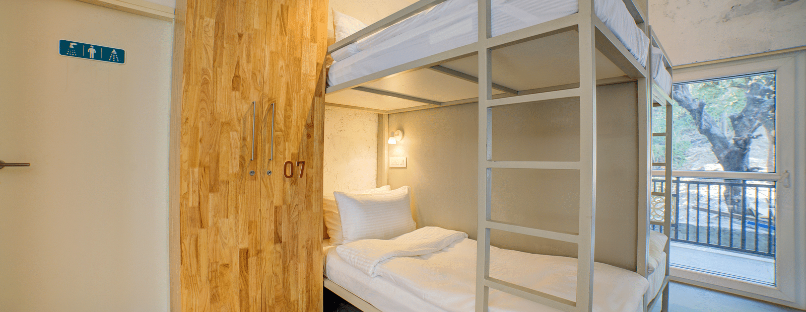 Bunk Beds with a ladder and a window in the back opening into a balcony - Bedzzz, Rishikesh