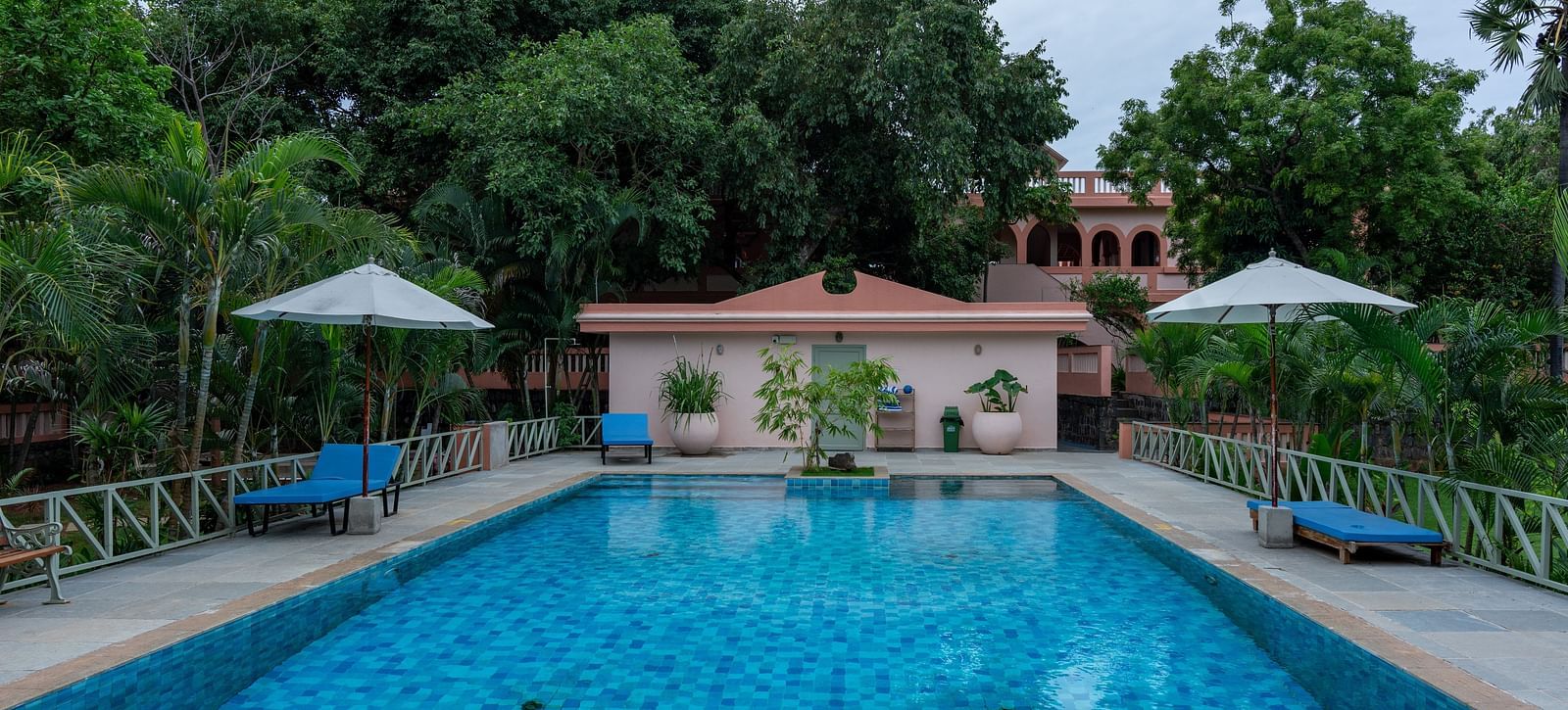 Swimming pool in front  of a property with lawn chairs