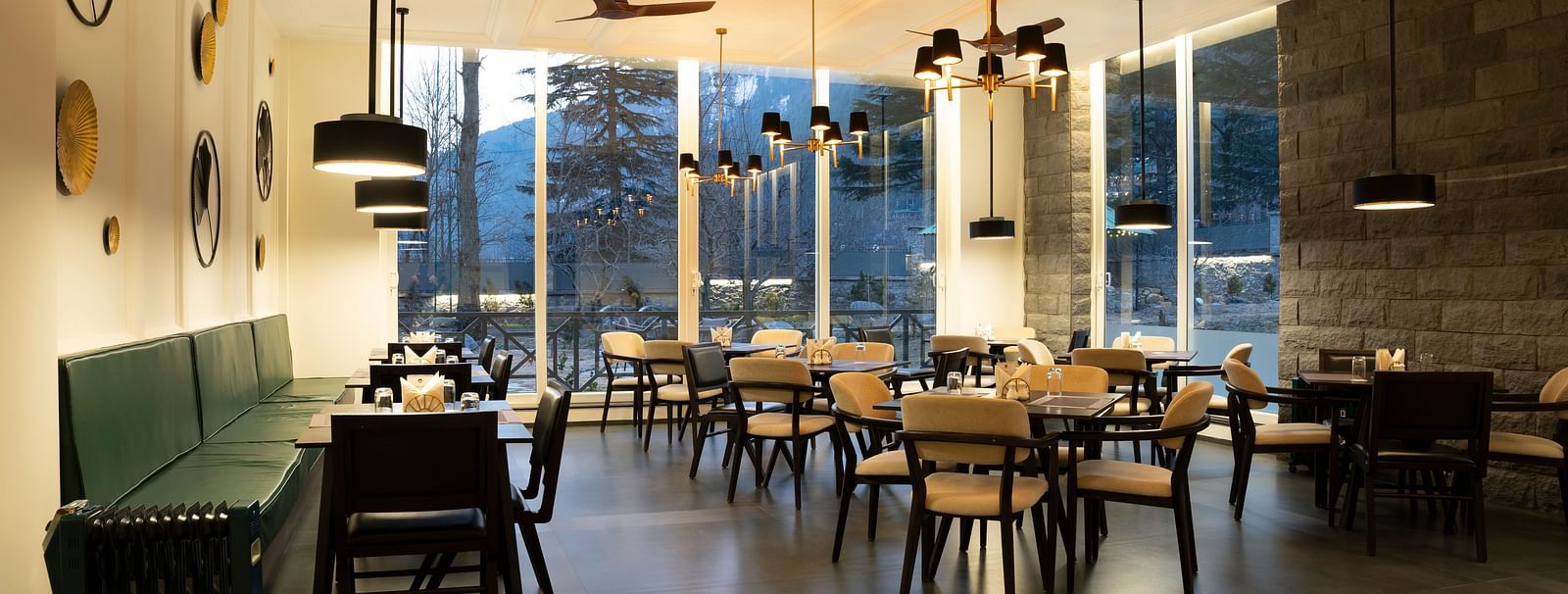 Bright dining area with floor-to-ceiling windows and elegant seating at Nivasana Manali.