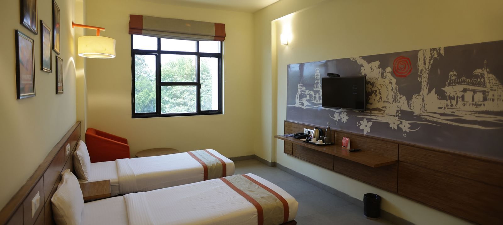 corner view image of a room with three single beds facing towards the wall mounted television - Max Hotel Jabalpur