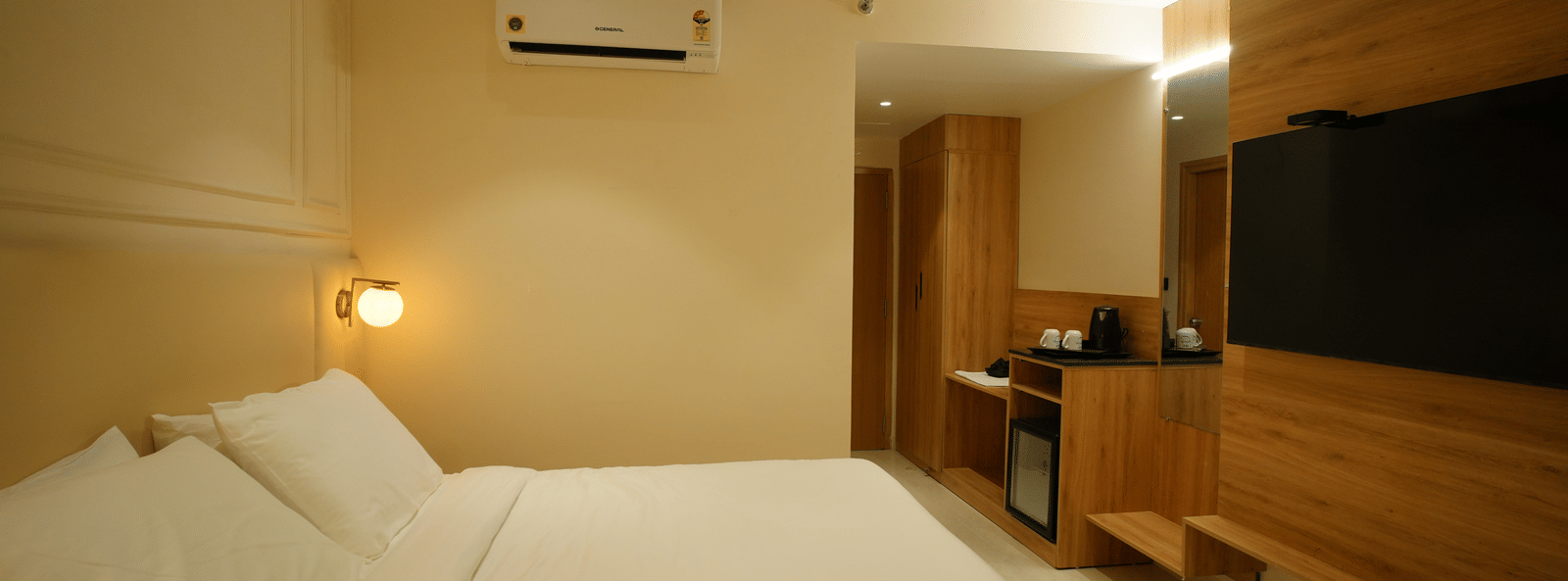  Bright room at Monday Premium, Madhapur, featuring a large bed with crisp white bedding and a wood-panelled wall with a TV.
