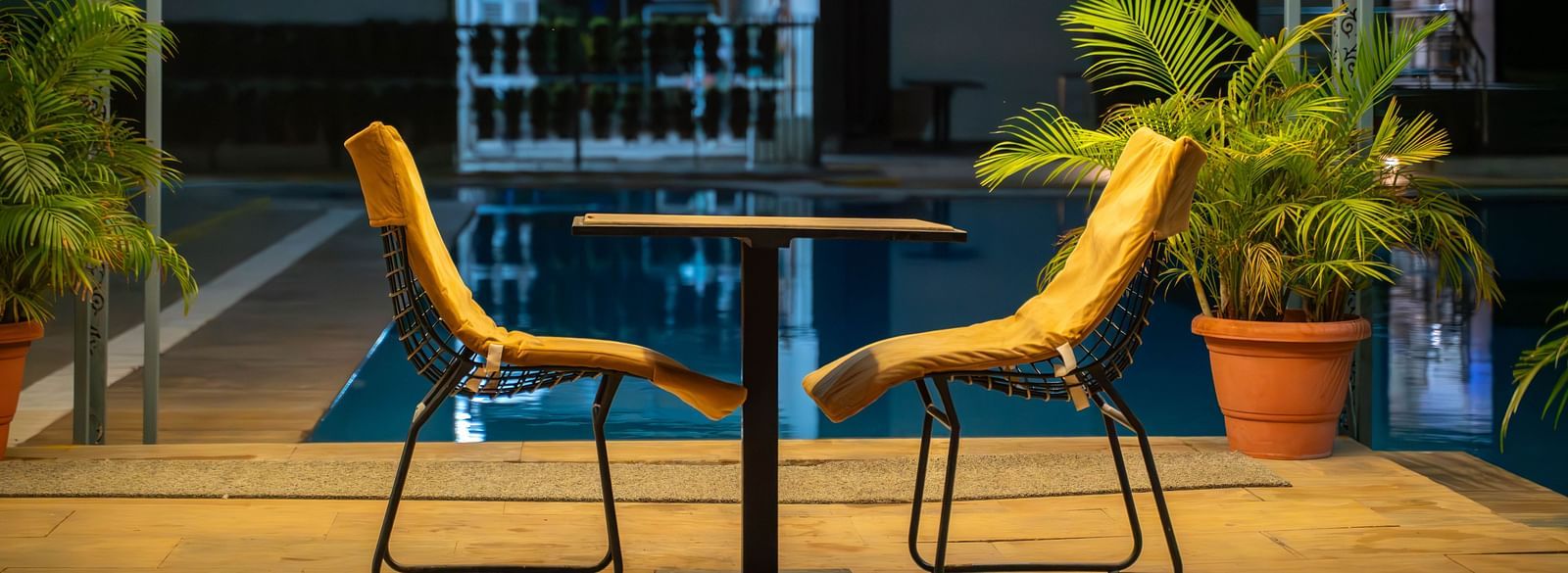 A dining table for two placed under romantic  lighting in an open poolside gazebo  at night in the Bamboo Saa Mulberry Resort in Pushkar.