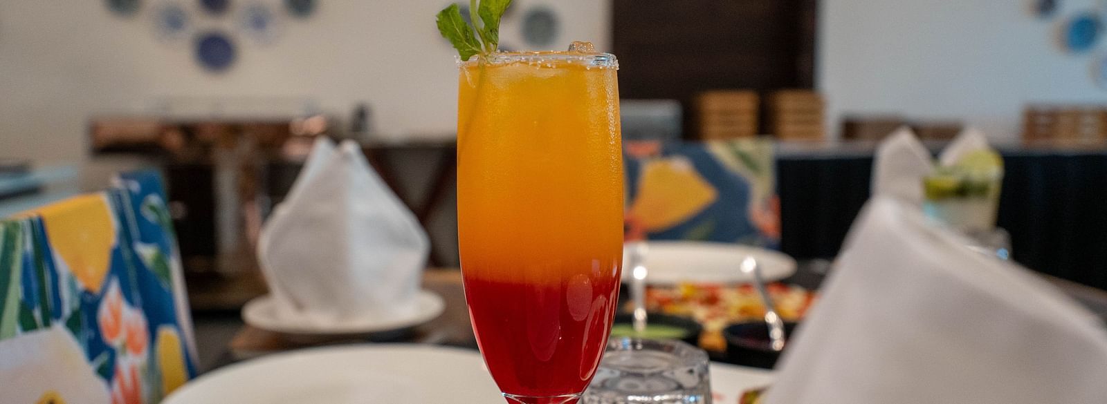 Focused picture of a colourful cold beverage placed on a neatly arranged dining table at the Bay Lead Restaurant in the Bamboo Saa Mulberry Resort in Pushkar.