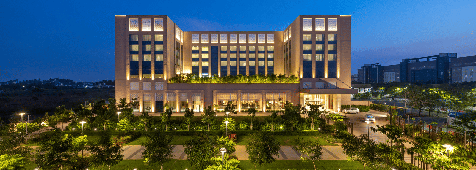 A striking twilight aerial perspective of the hotel, surrounded by manicured lawns - Grand Madurai by GRT Hotels