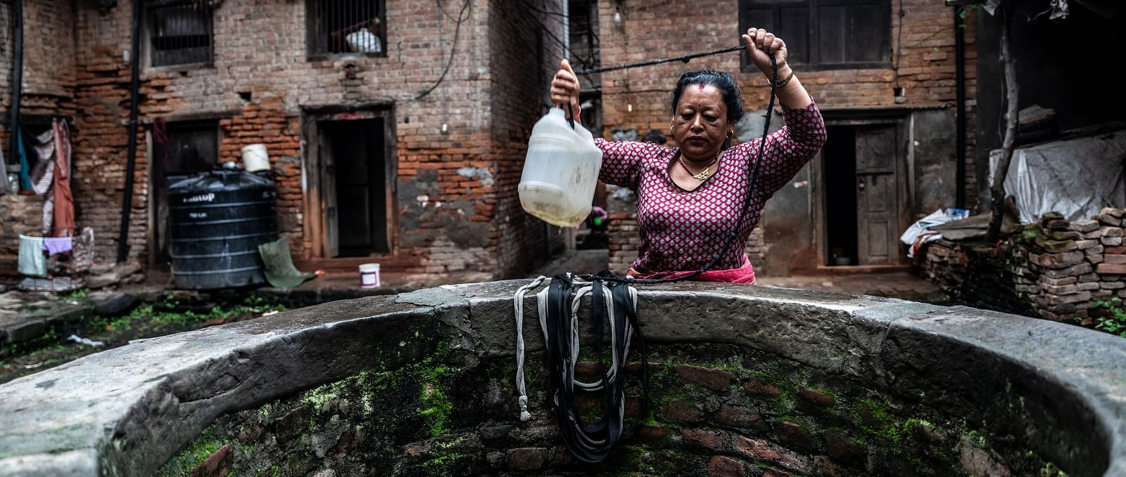 A woman fetching water from a well with a bucket