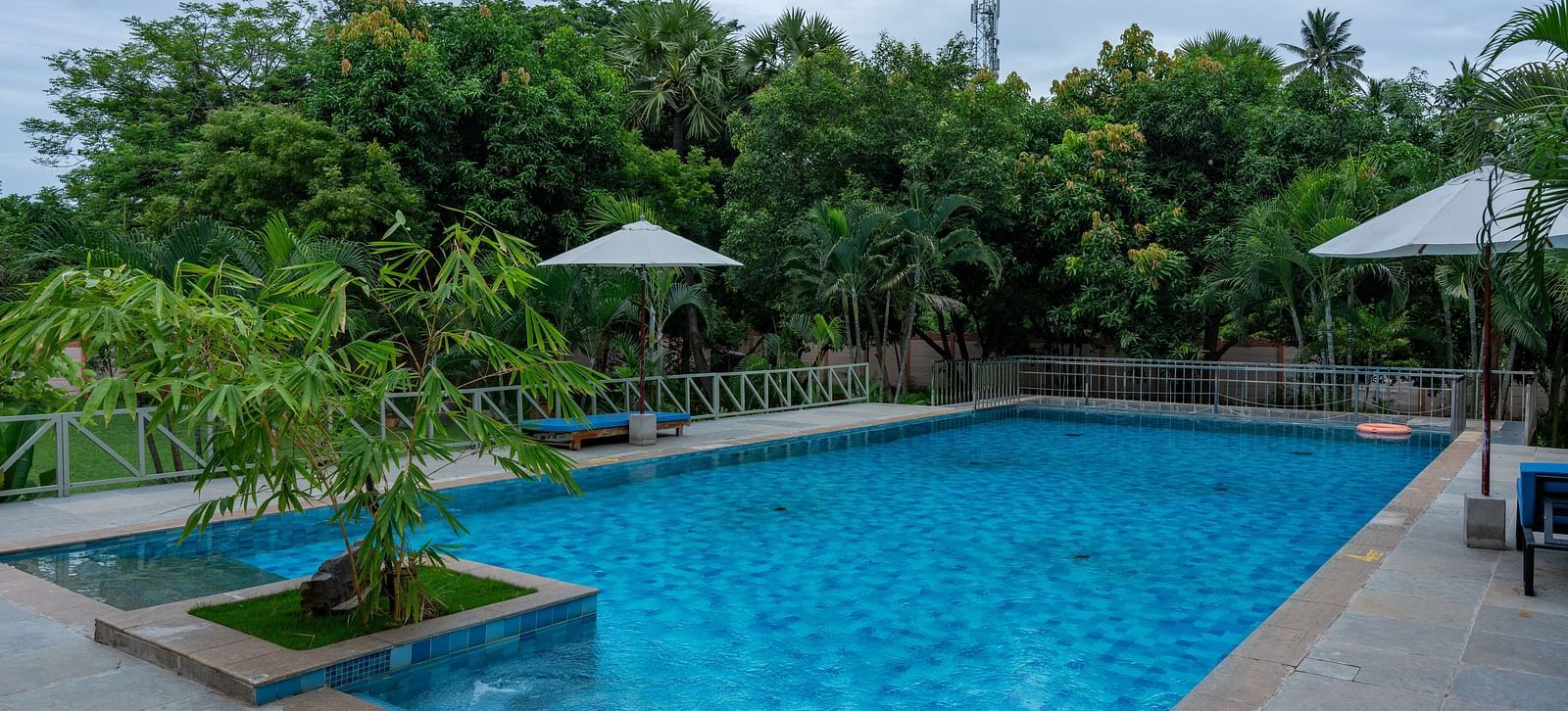 Side view of  swimming pool in front  of a property with lawn chairs