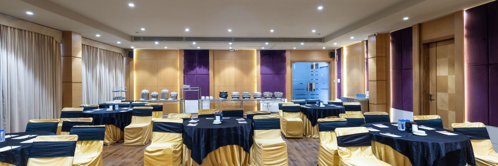 Banquet hall, Iris, with tables in cluster seating arrangment, wooden flooring, seen at Pravasa Stay Vijay Nagar, Indore.