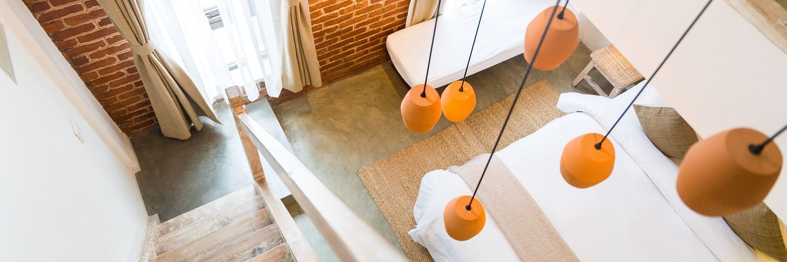 An aerial shot of the deluxe loft room with a staircase and chandelier hanging above it - The Nanee