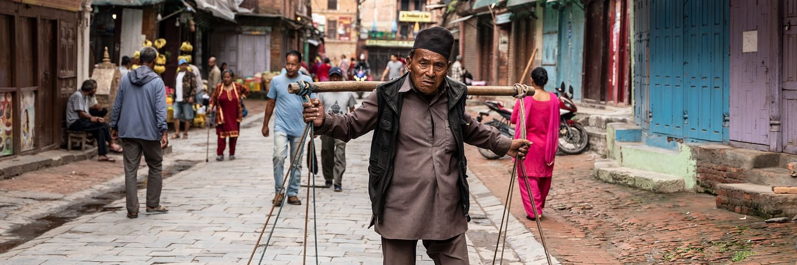 A man carrying vegetables on bamboo baskets attached to a pole