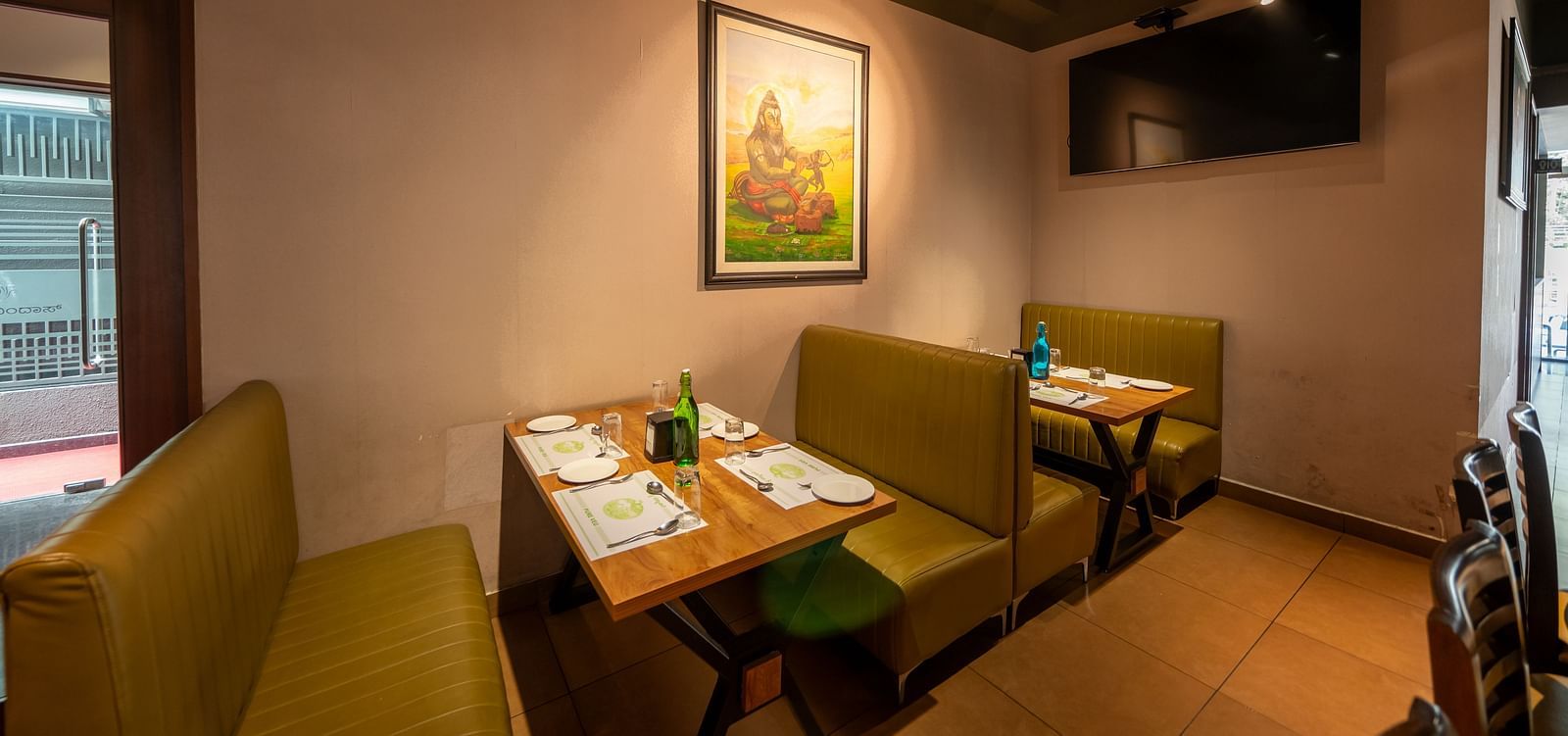 Image of a dining section with seating area and a photo frame mounted on the wall at Hari Govindas, Siddappa Square.