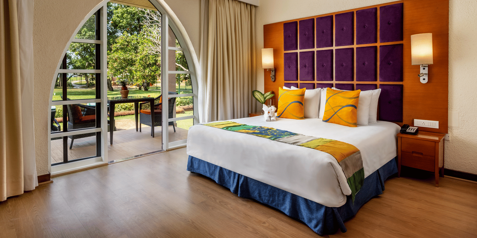 a double bed with cushioned headboard, lamps and side tables inside 2 Bedroom Garden Villa - Caravela Beach Resort Goa