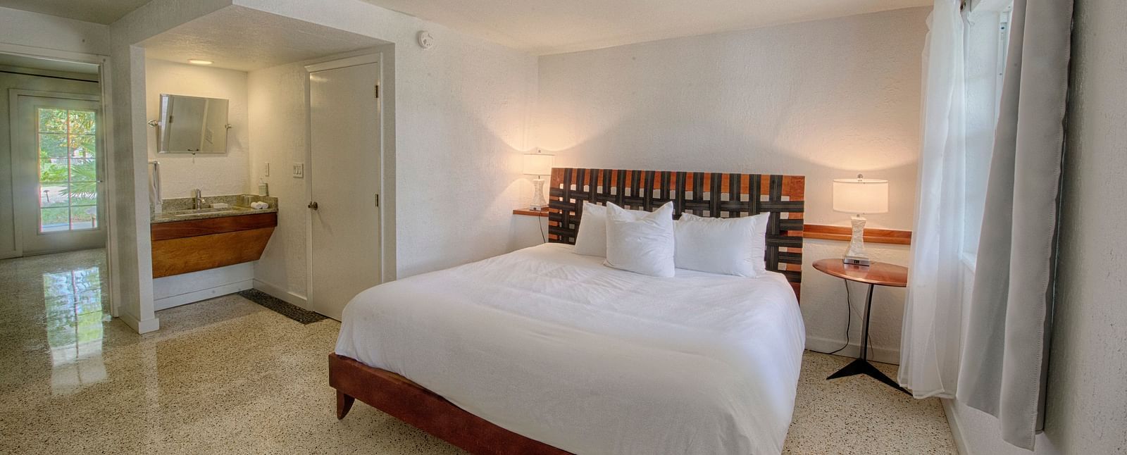 Bedroom at Casa Morada with a king bed, wooden headboard, and a sitting area near large windows.