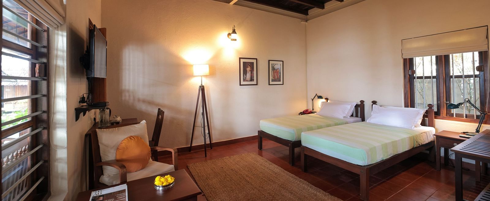 Twin beds placed in front of a desk in Lake Front Verandah Room at Samiira on Ashtamudi Lake. 