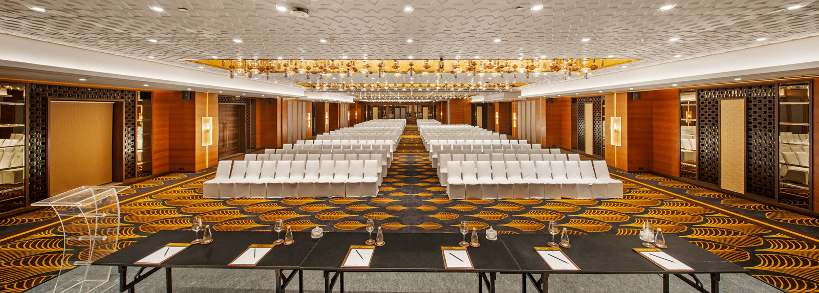 Banquet hall featuring a luxurious golden ceiling and rows of white chairs at Radisson BLU