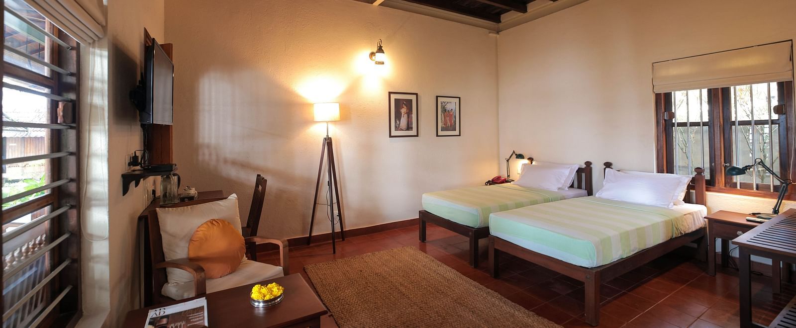 Twin beds placed in front of a desk in Lake Front Verandah Room at Samiira on Ashtamudi Lake. 