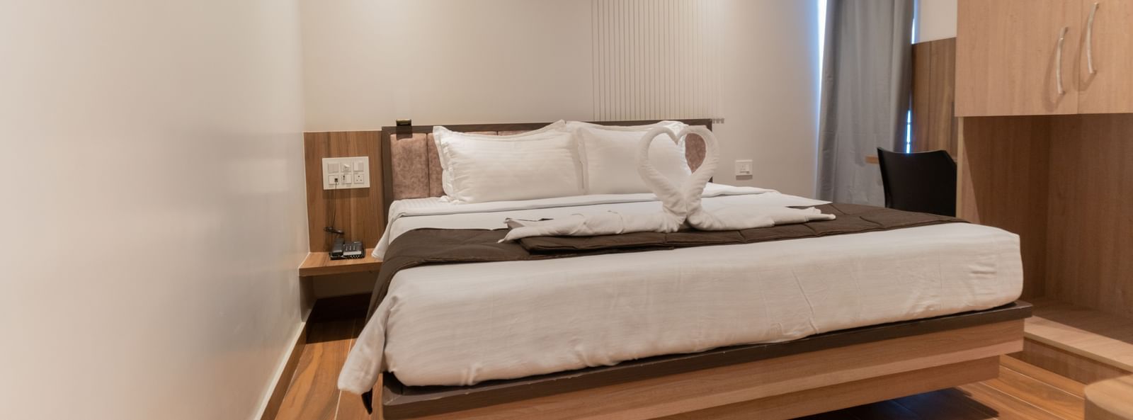 Spacious bedroom with wooden flooring and a comfortable double bed at Beestay Hotels, Rajahmundry.