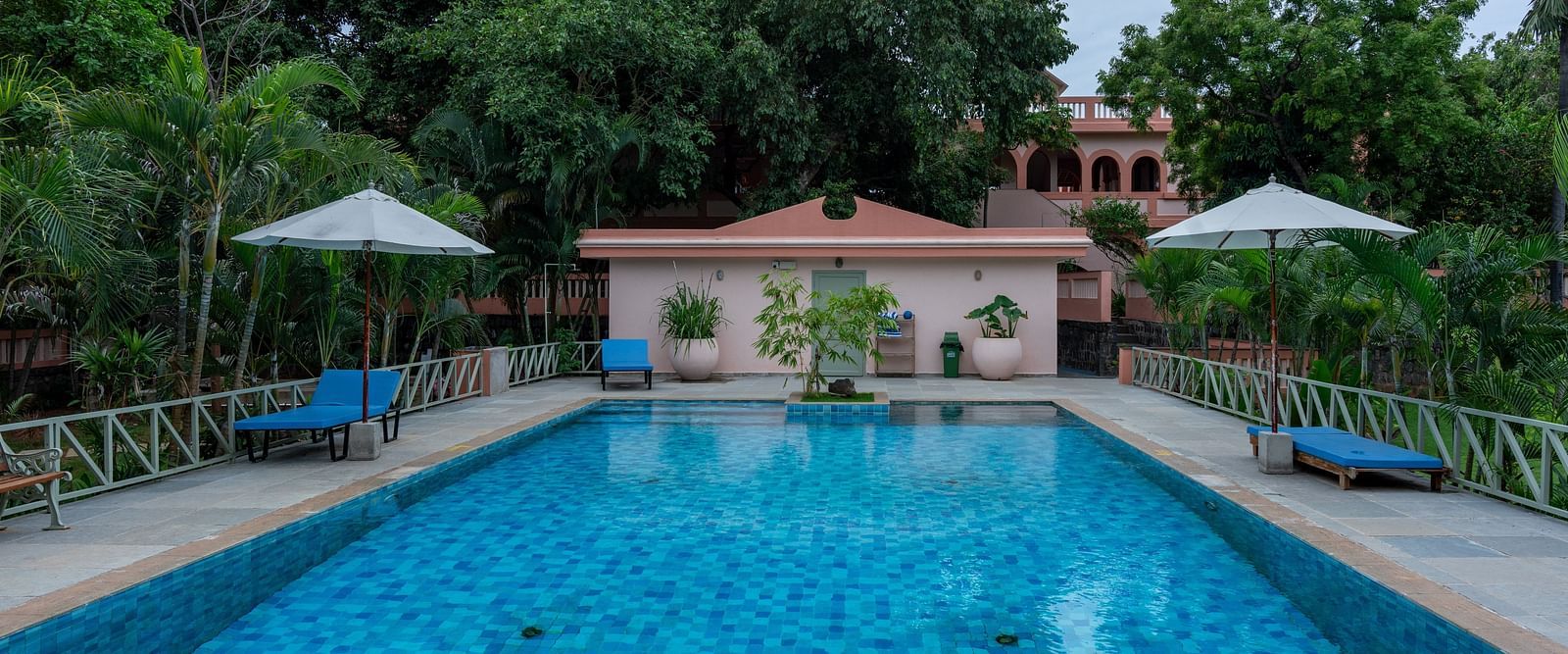Swimming pool in front  of a property with lawn chairs