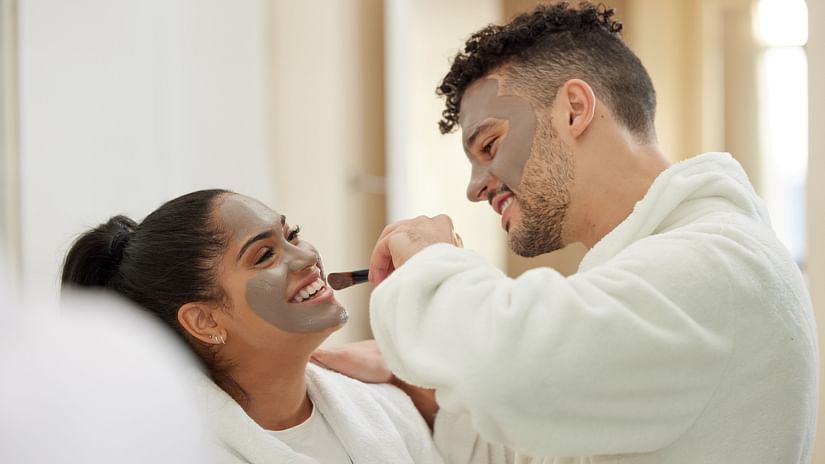 A happy couple wearing white bathrobes, undergoing spa treatment while having a face mask.