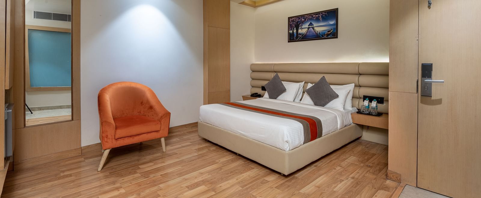 The deluxe room at DLS Hotel Arihant, Haridwar with a bed, bed side tables, a chair, and other room amenities