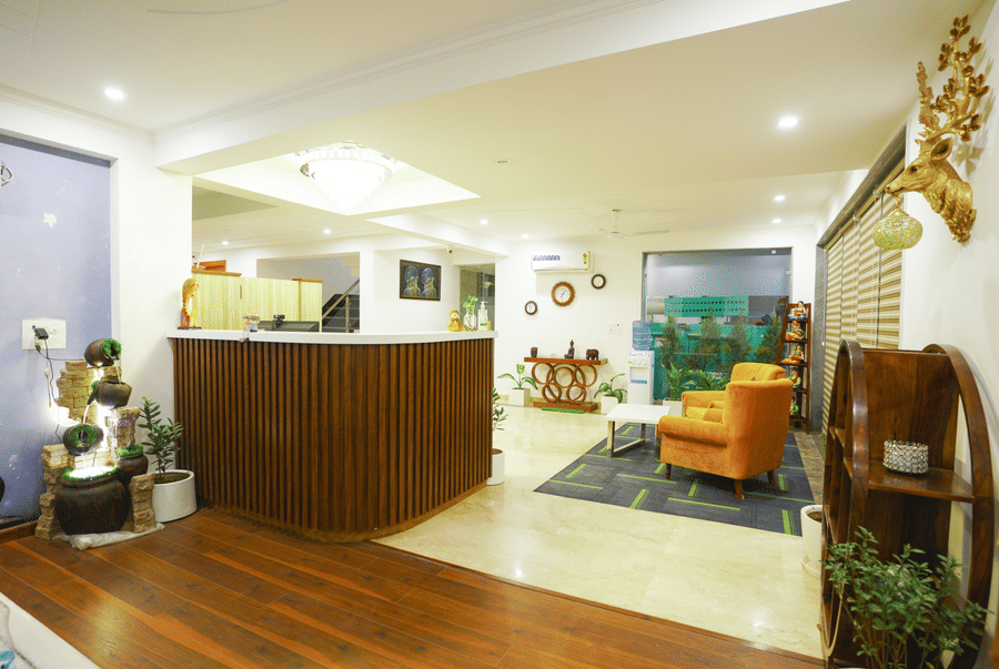 Reception desk and lobby with a yellow armchair and indoor plants at Lime Tree Hotel, Pulkit, Gurgaon