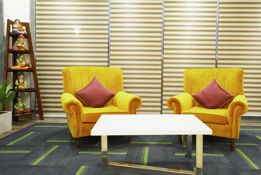 Shared lounge with two yellow armchairs and a white coffee table at Lime Tree Hotel, Pulkit, Gurgaon