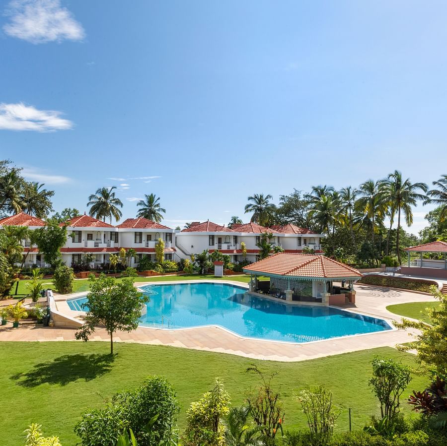 A view of the Poolside Lawn with a swimming pool, a spacious green garden, and large trees surrounding the area