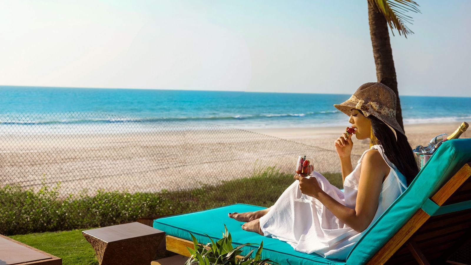 a woman sitting on a lounger in front of the sea - Caravela Beach Resort Goa