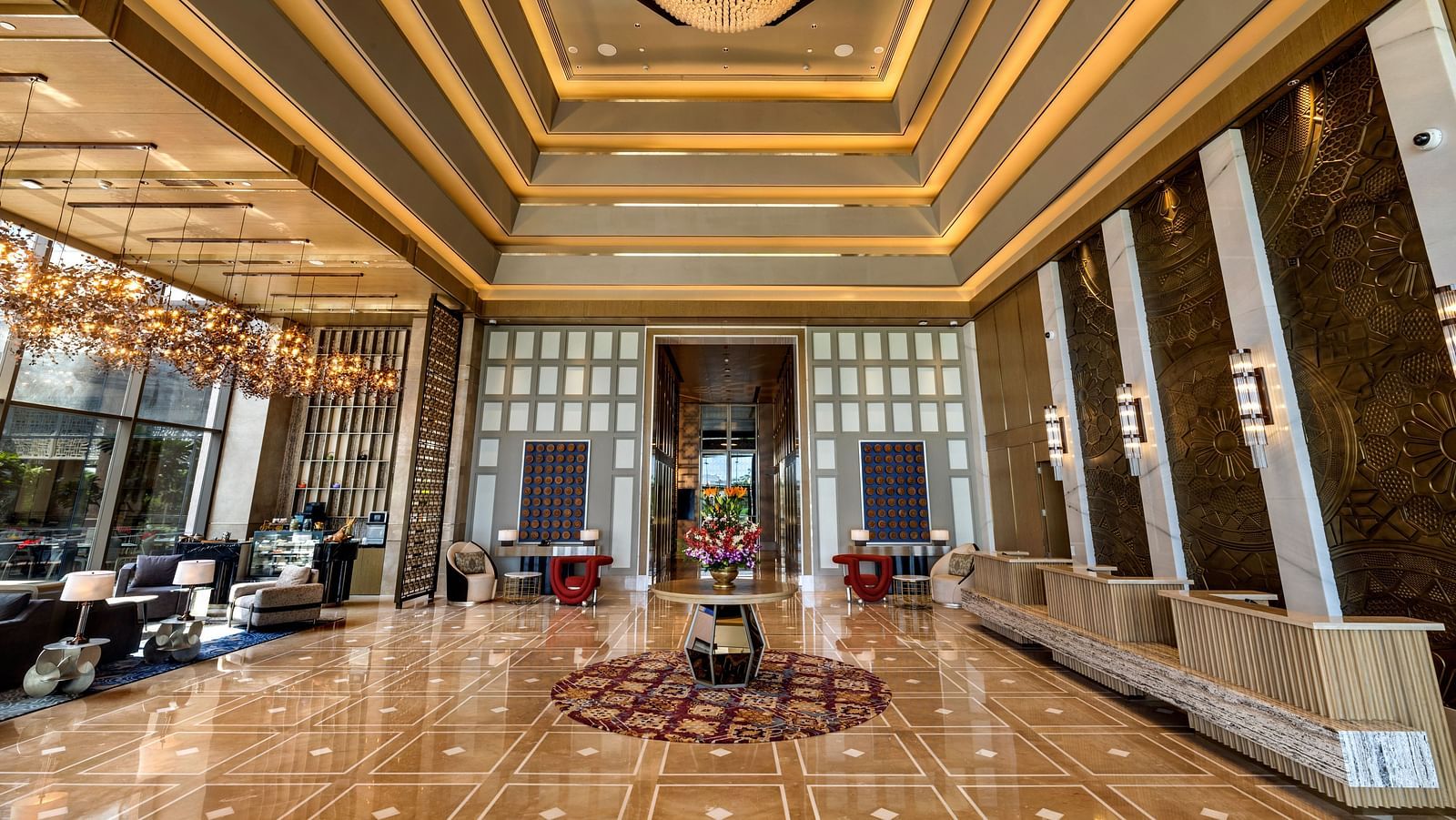 A wide angle shot of the hotel lobby with a vase at the centre below a chandelier - Grand Madurai by GRT Hotels