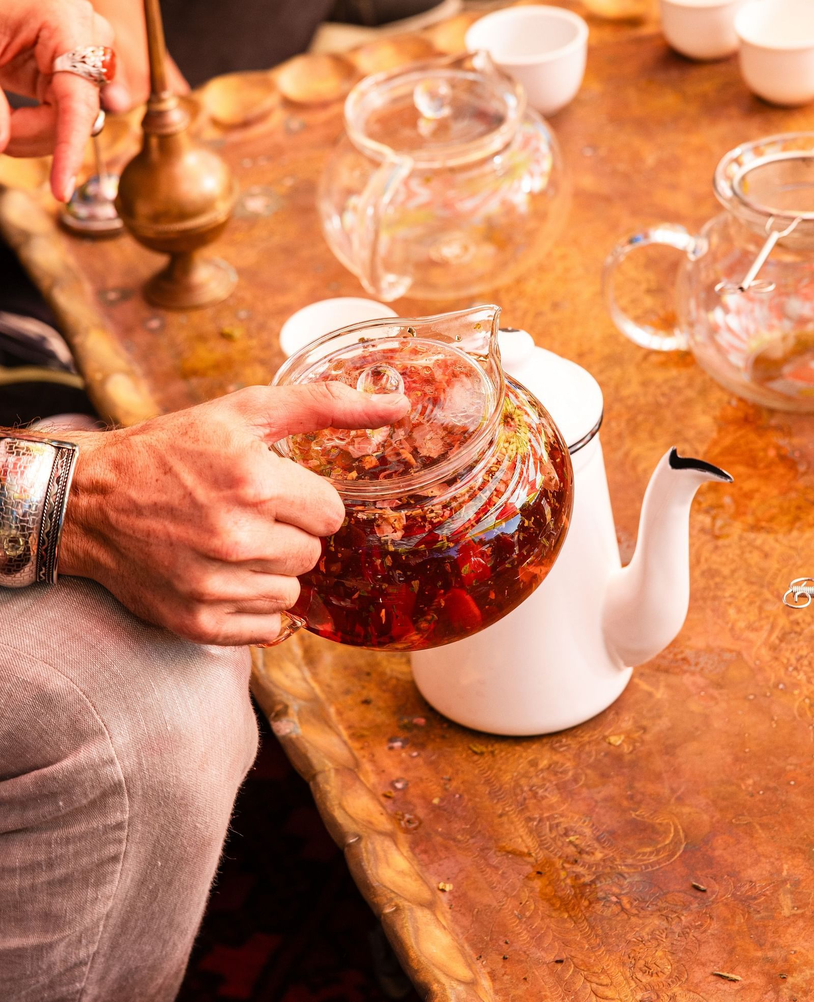 Close-up of a person pouring tea during an outdoor tea ceremony with glassware and traditional setup.