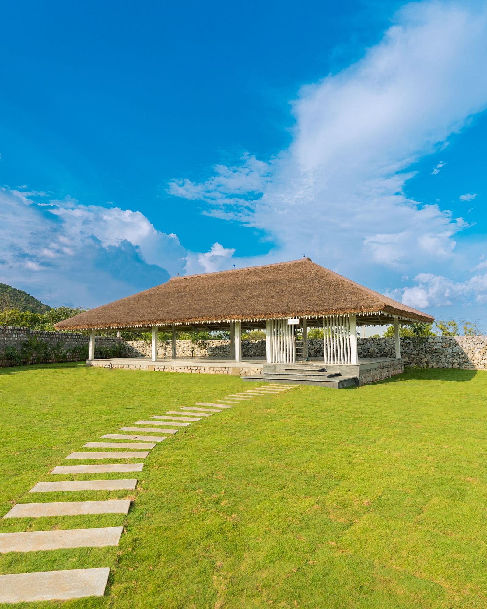 image featuring an expansive green lawn with a tile pathway leading towards a sun shade at the slice of heaven - Darza Resorts