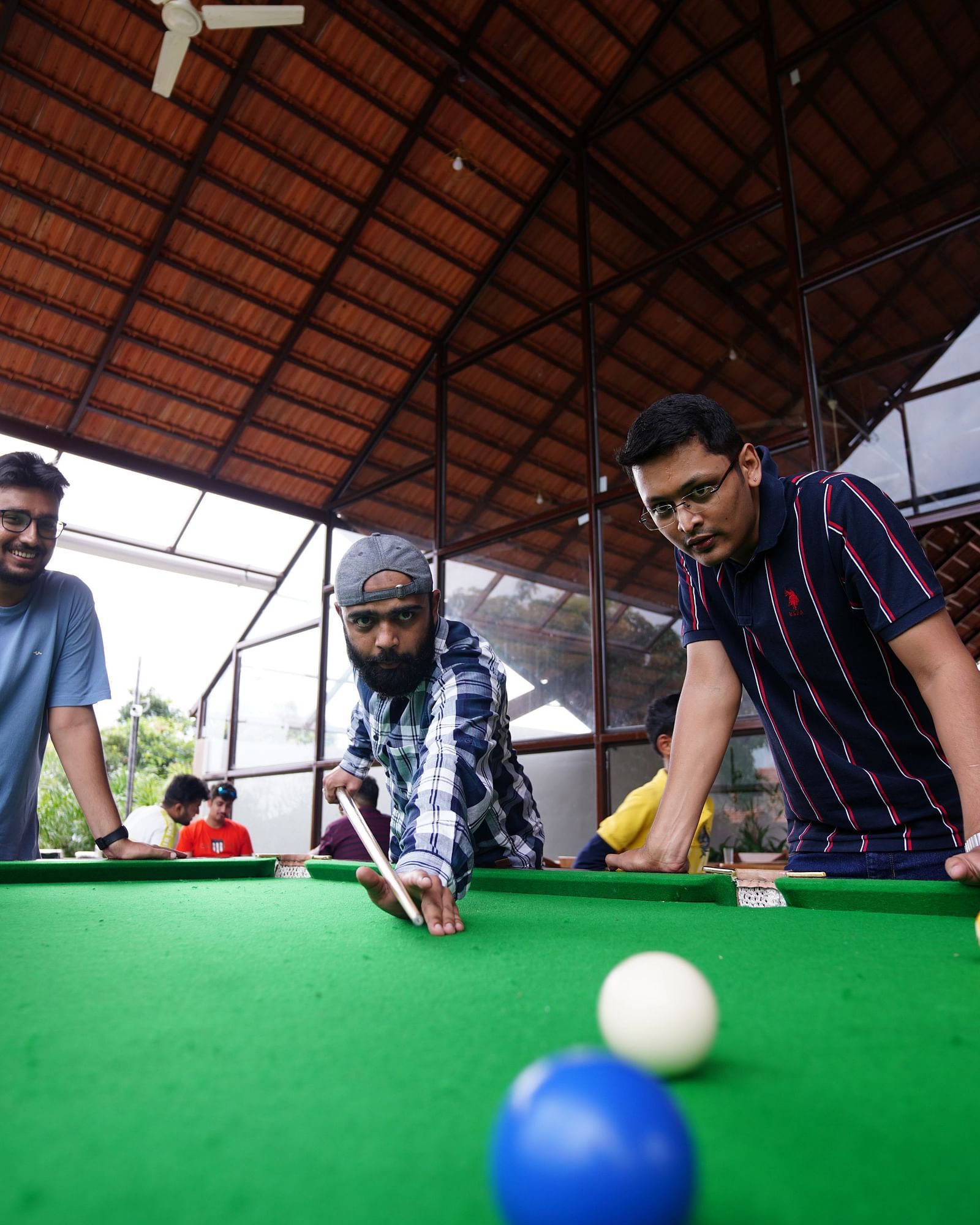 A group of people focused on snookerl with one person making the shot at Ravishing Retreat