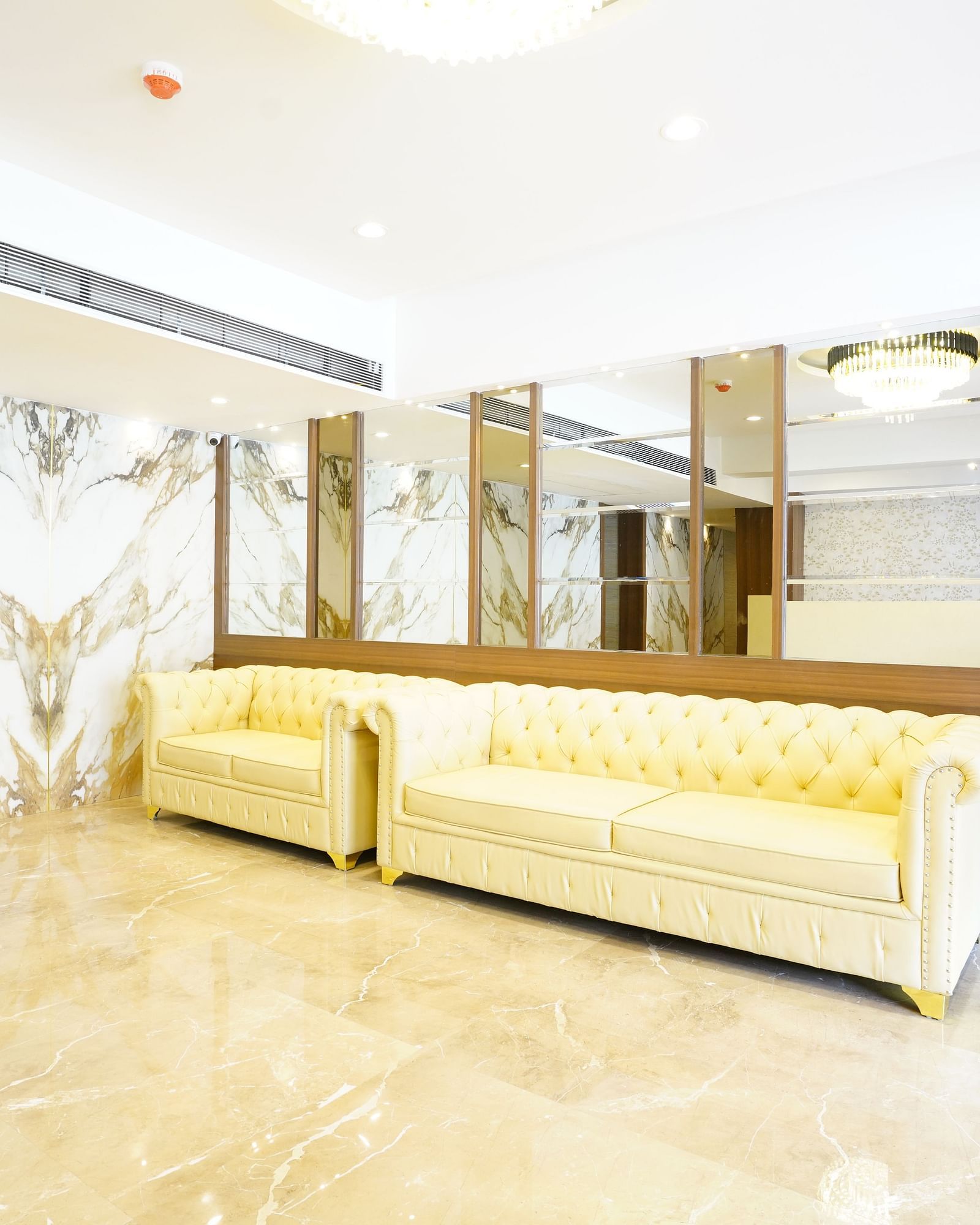 An elegant lobby featuring a seating area with two yellow sofas and mirrored wall at Shyanu Lords Eco Inn Airoli.