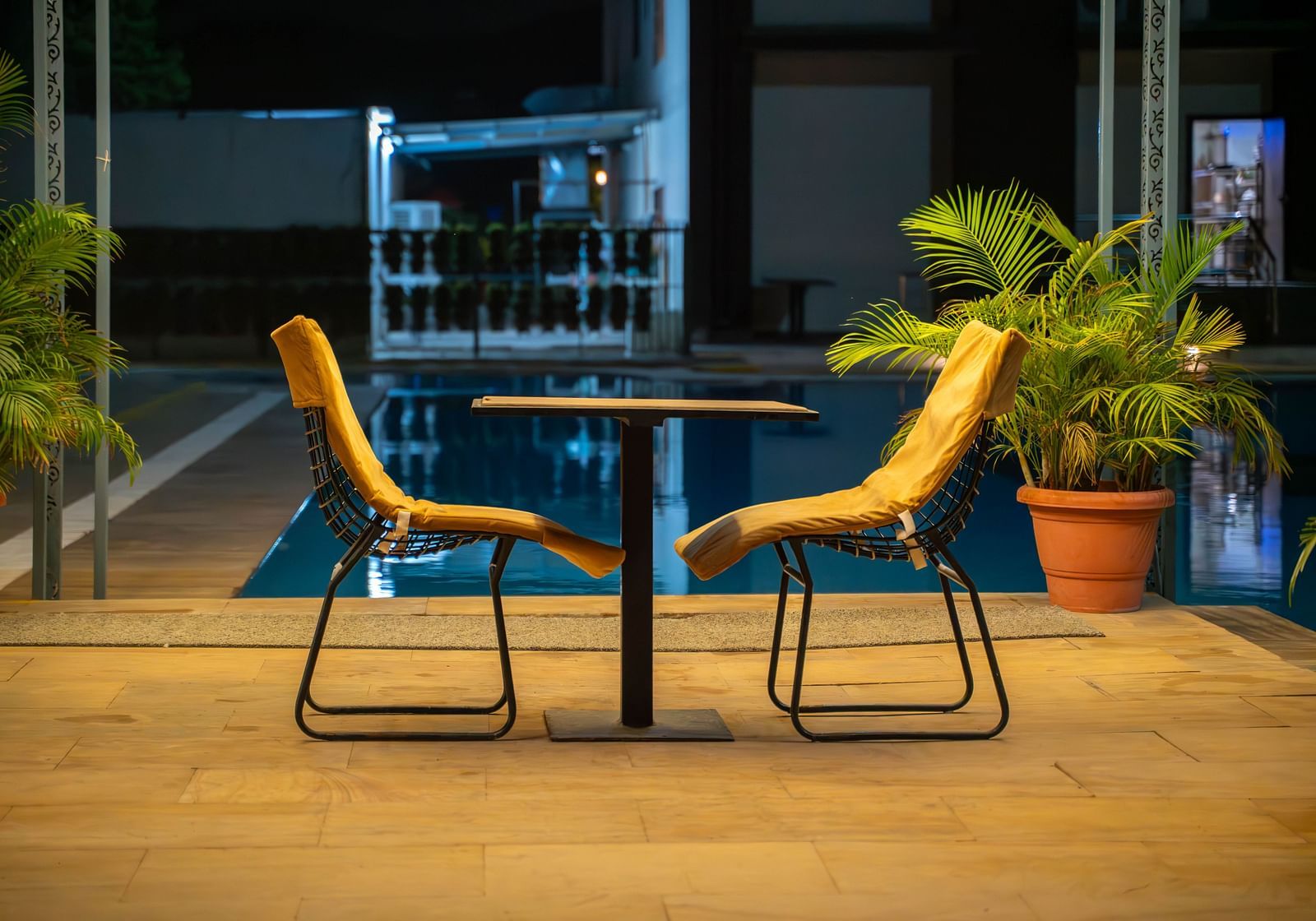 A dining table for two placed under romantic  lighting in an open poolside gazebo  at night in the Bamboo Saa Mulberry Resort in Pushkar.
