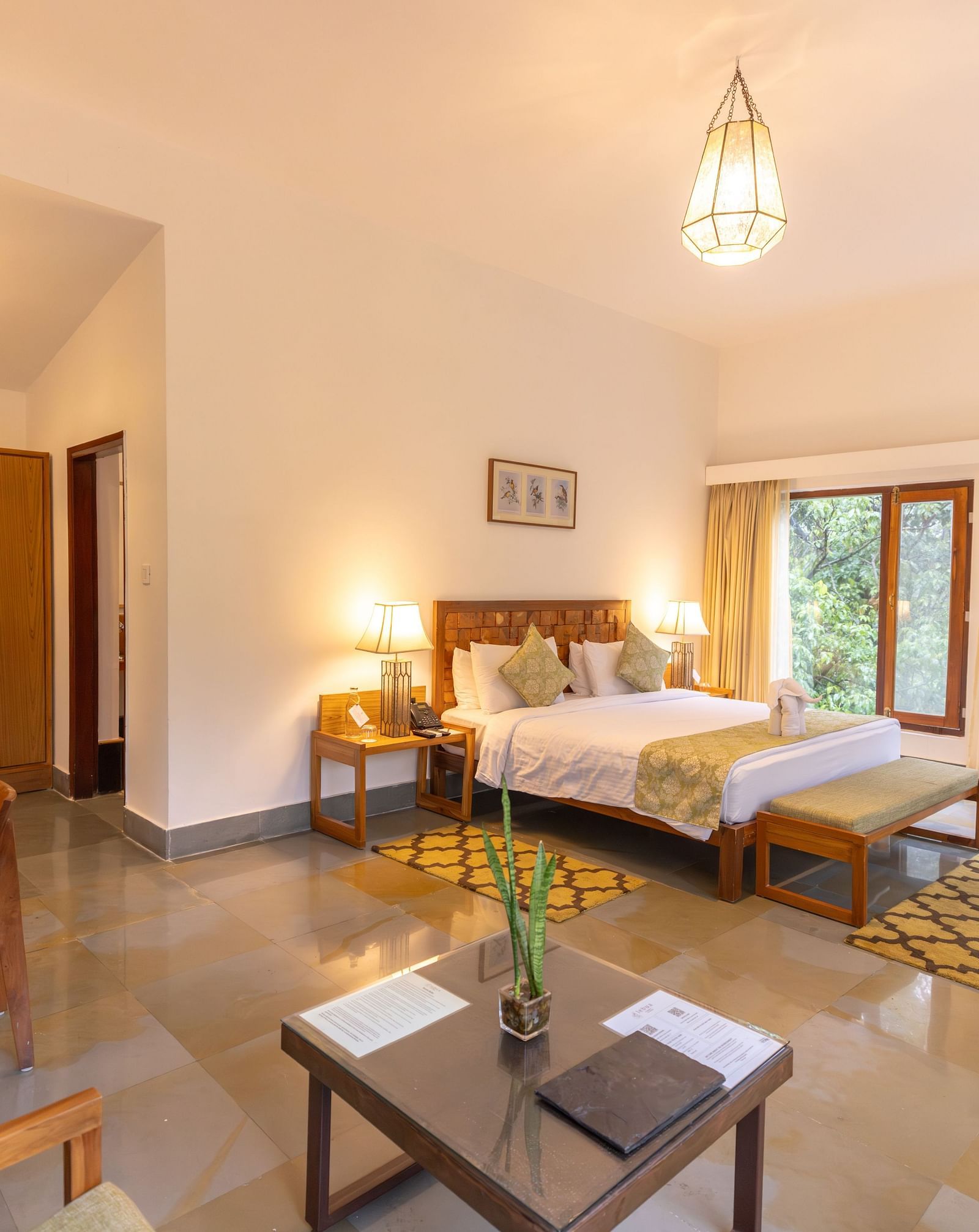 Premium Suite at Saraca Resort & Spa Corbett with a double bed, a sofa chair and a work desk and chair