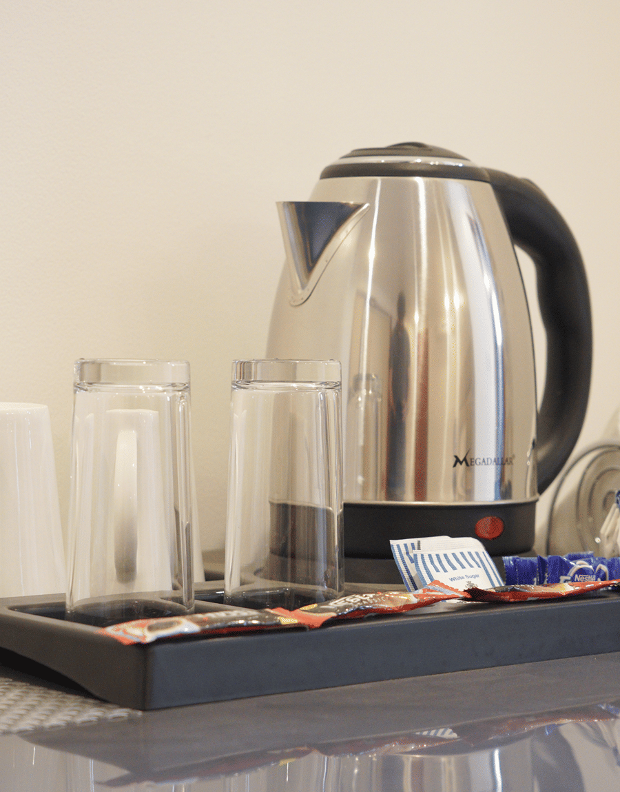 Electric kettle, glasses and tea and coffee sachets on a tray in the Deluxe Room at Lime Tree Hotel, Pulkit