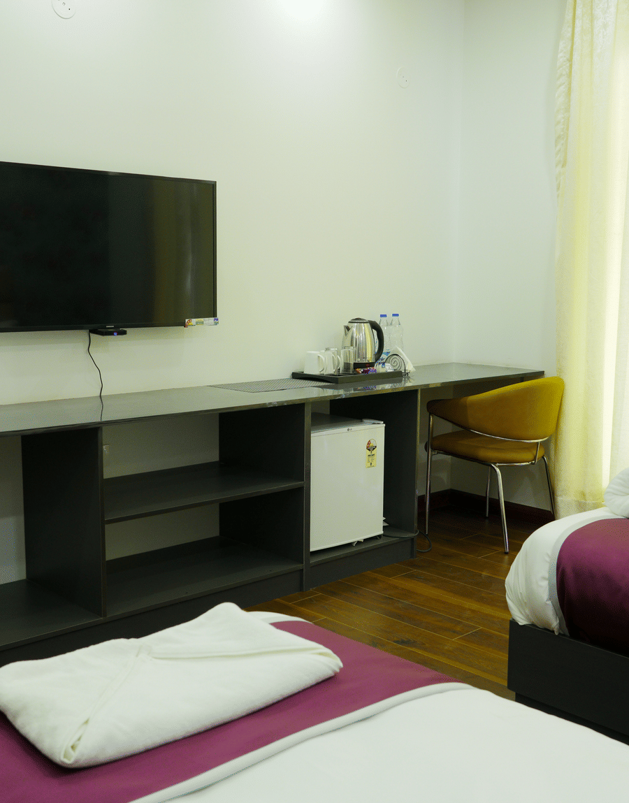 Wall-mounted TV, work desk and minibar in the Deluxe Room with Balcony at Lime Tree Hotel, Pulkit, Gurgaon