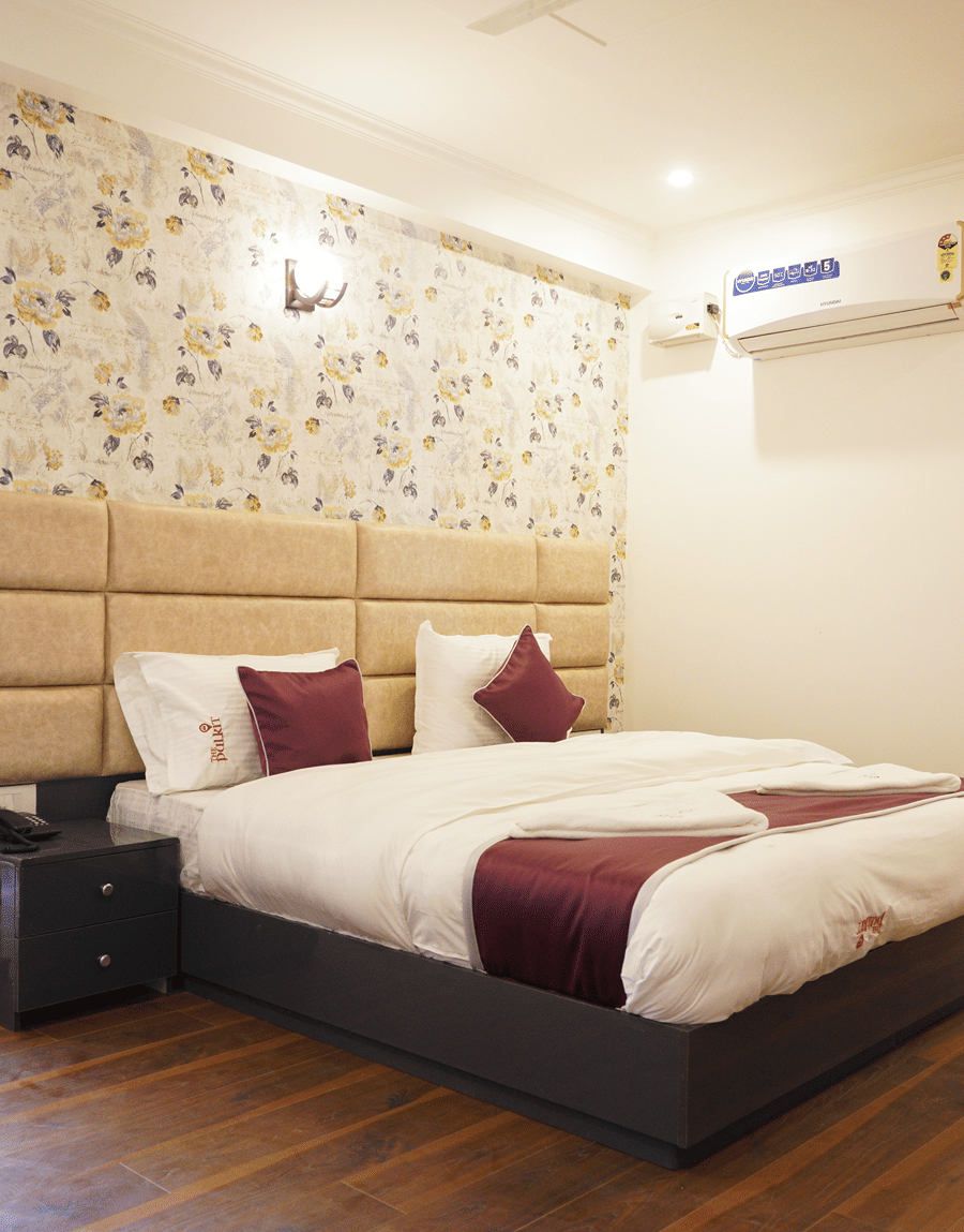 Double bed with floral wallpaper and a padded headboard in the Deluxe Room with Balcony at Lime Tree Hotel, Pulkit