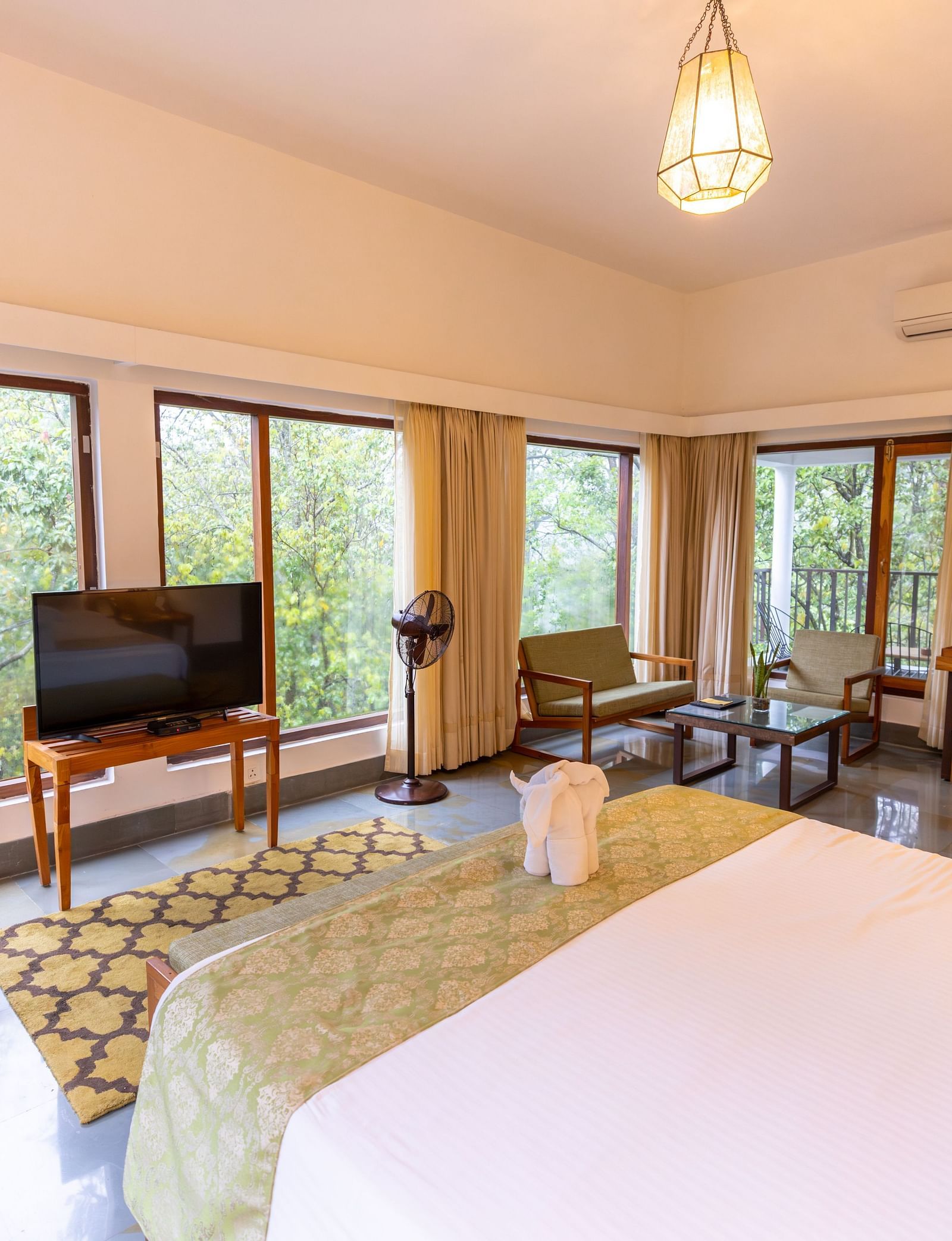 Premium Suite at Saraca Resort & Spa Corbett with a double bed, a television and large windows surrounding the room