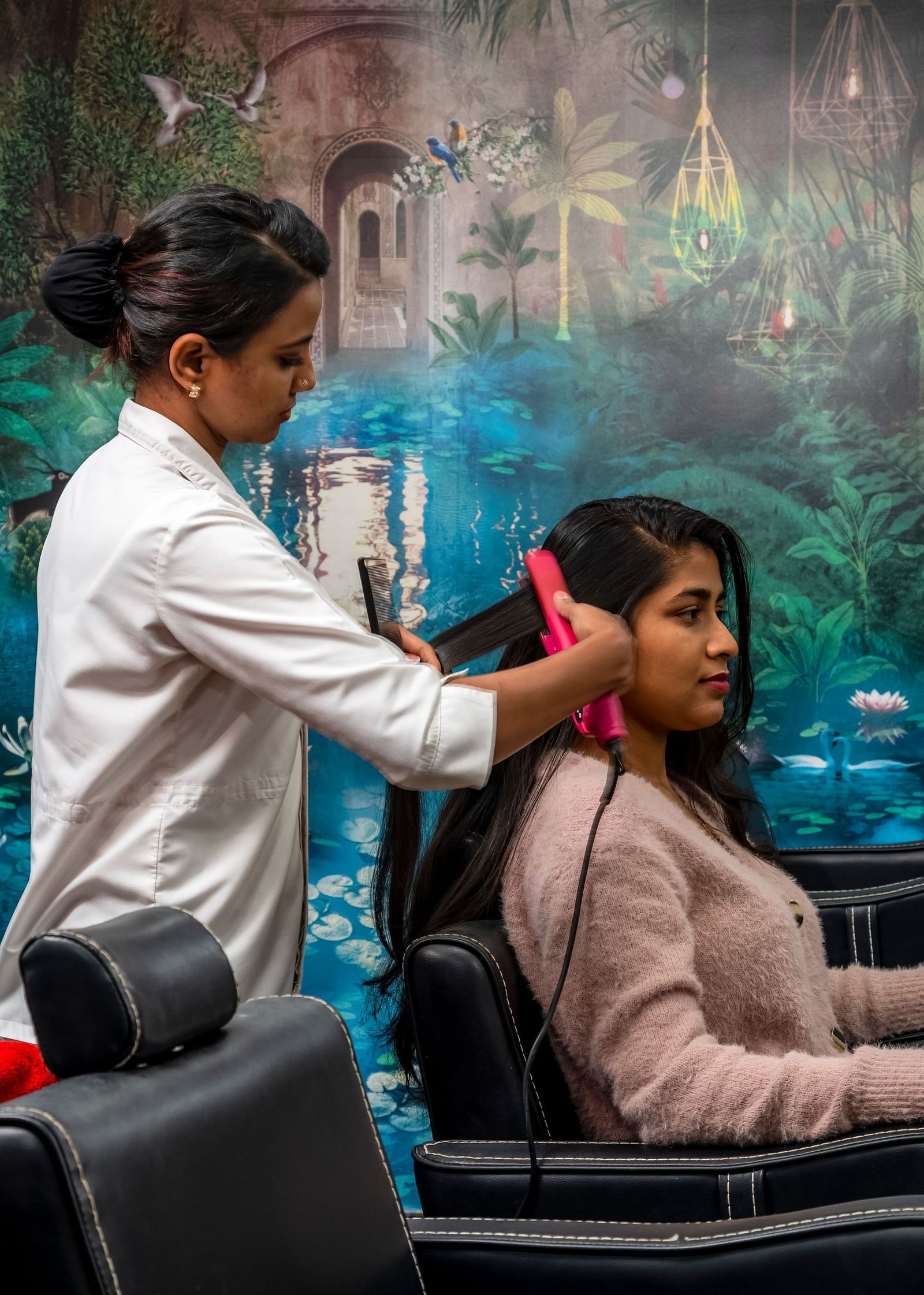 a stylist working on the hair of a customer sitting on the chair - Caravela Beach Resort Goa