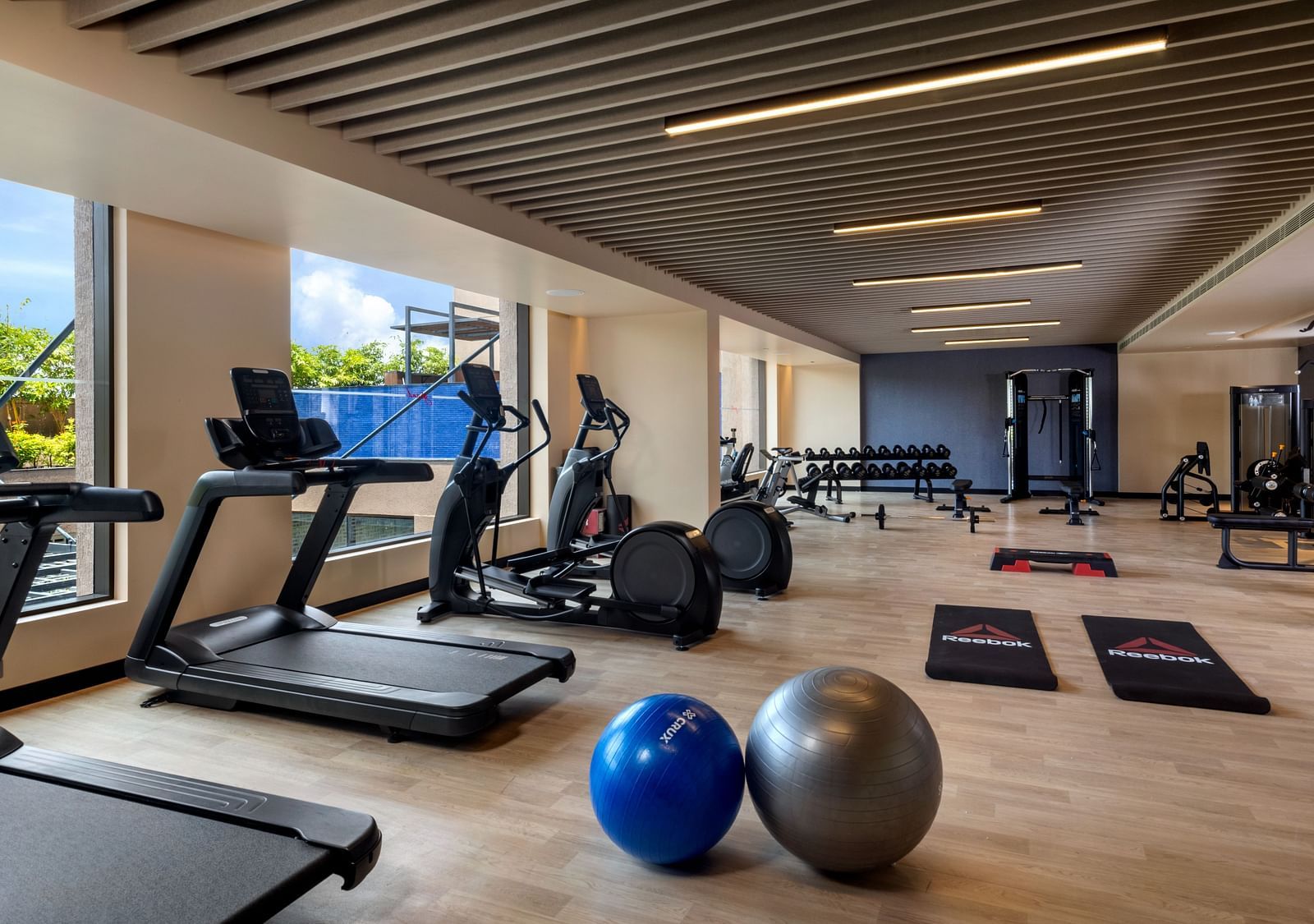 A modern hotel gym, equipped with various exercise machines and weights - Grand Madurai by GRT Hotels