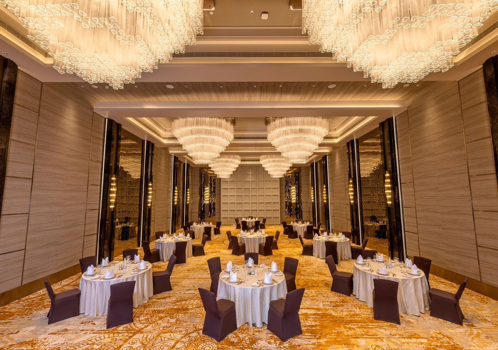 Grand banquet hall setup for a formal event with circular tables and chandeliers - Grand Madurai by GRT Hotels