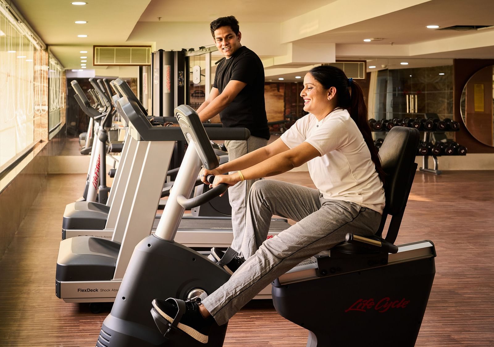 An image of a woman doing an exercise with a trainer helping along at Grand Vijayawada by GRT Hotels.