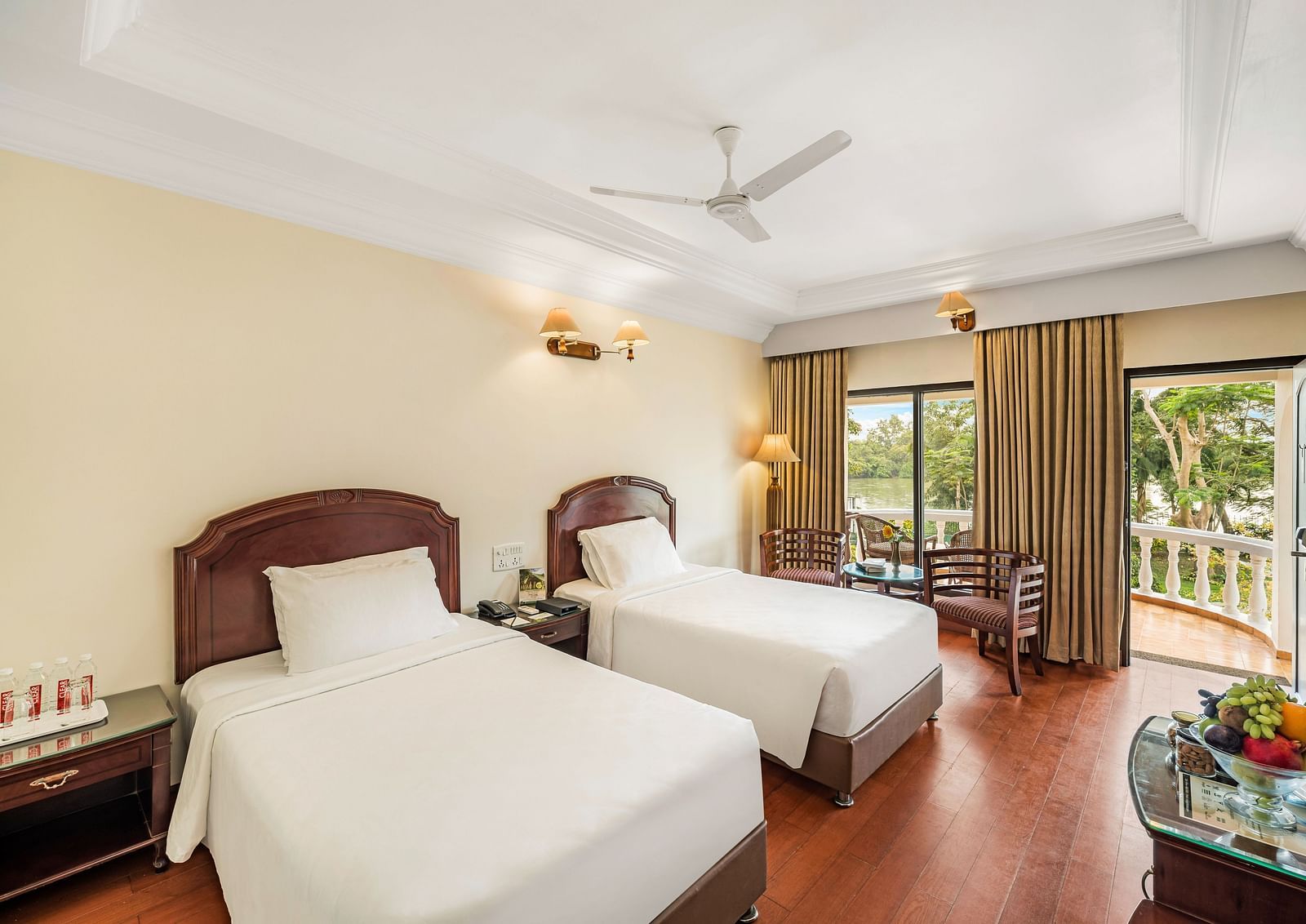 An image of the River View Room With Verandah featuring two single beds, bed side table, lamps, flat screen TV, and chairs - GReaT Trails River View Resort Thanjavur By GRT Hotels