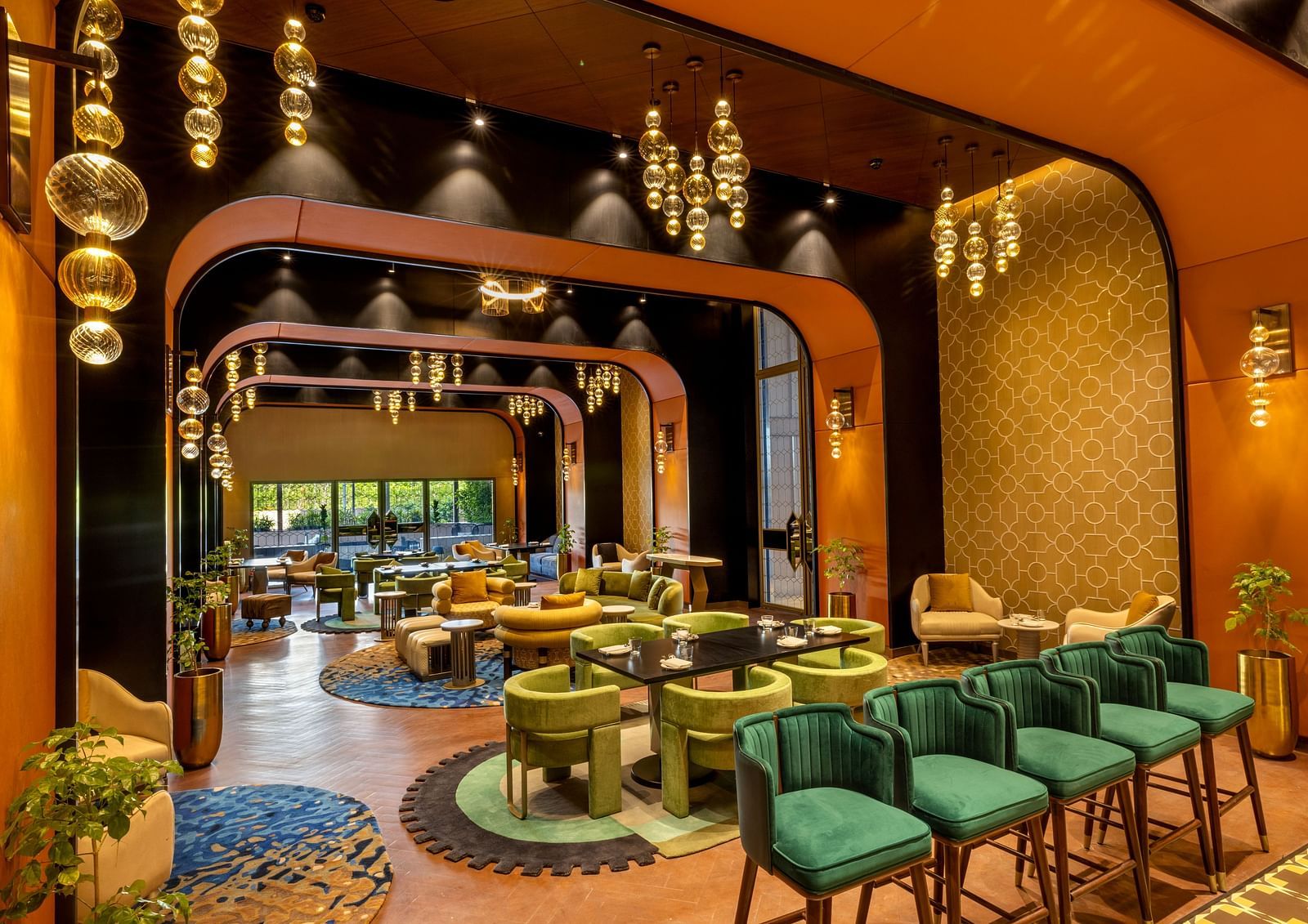 A stylish restaurant interior features modern green seating and decorative lighting fixtures - Grand Madurai by GRT Hotels