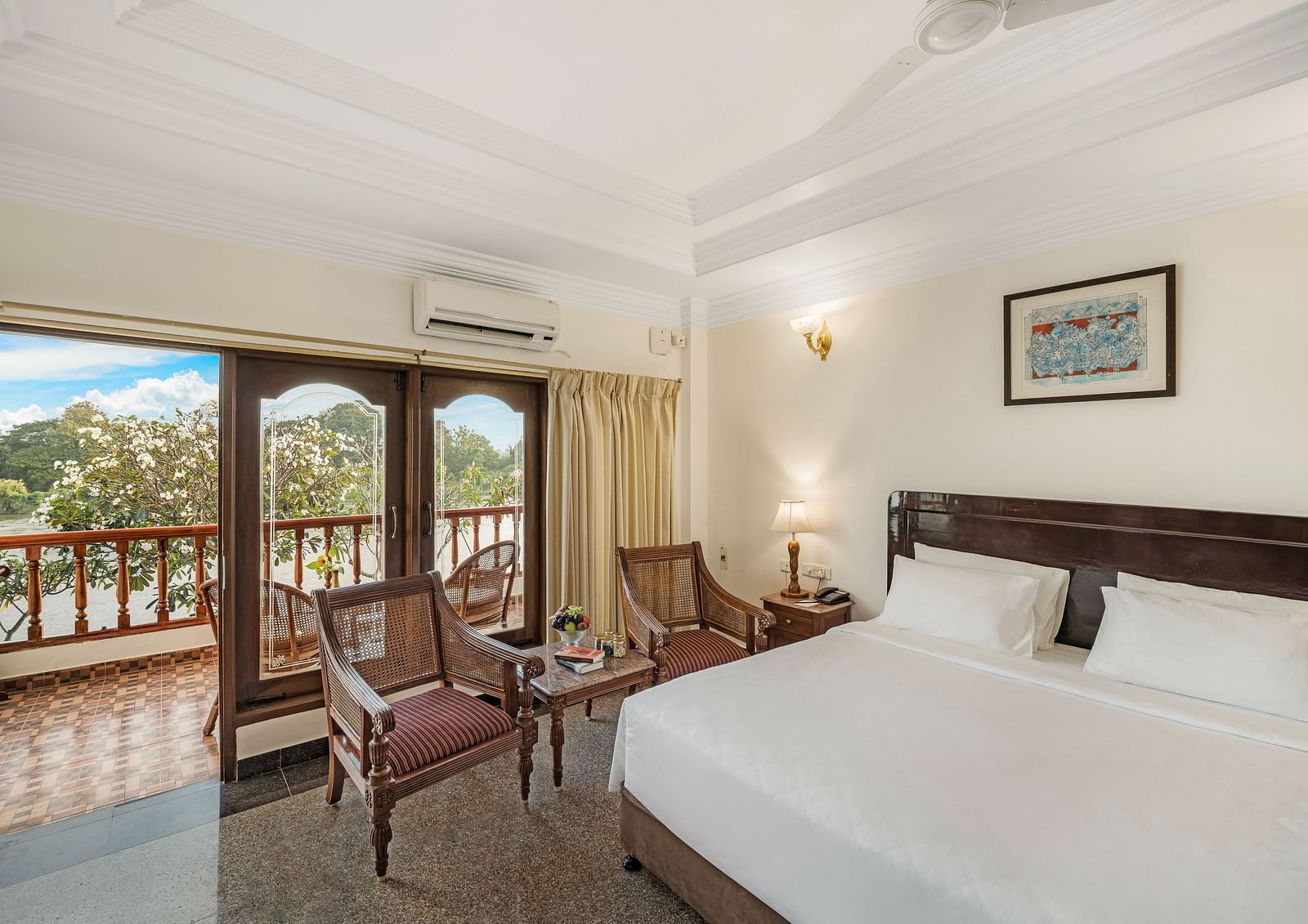 An image of the River Edge Heritage Room featuring a queen size bed, bed side table, lamps, and chairs - GReaT Trails River View Resort Thanjavur By GRT Hotels