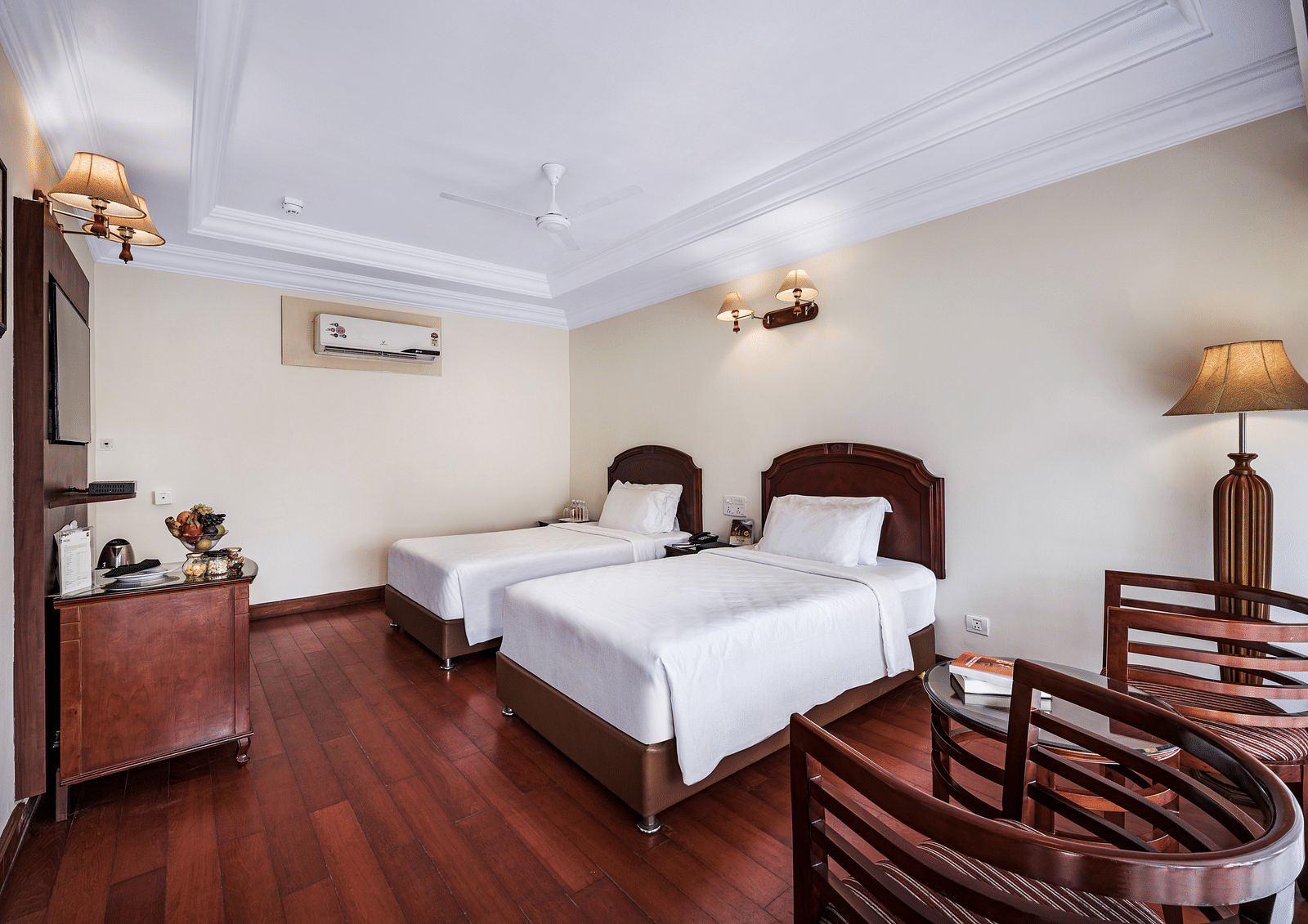 An image of the River View Room With Verandah featuring two single beds, bed side table, lamps, flat screen TV, and chairs - GReaT Trails River View Resort Thanjavur By GRT Hotels